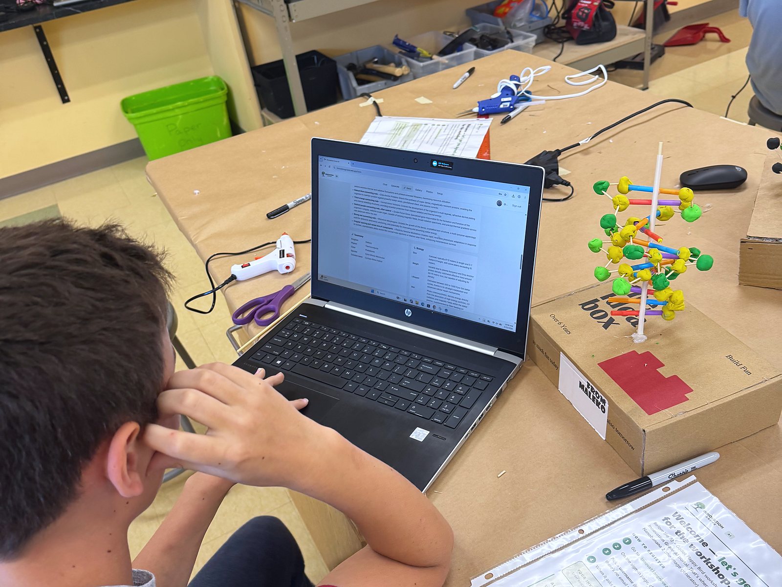 A student at a laptop with the DNA model he built beside him